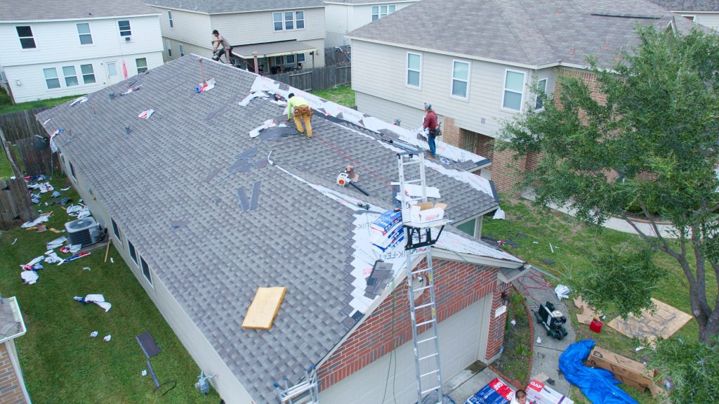 How to Perform a DIY Roof Inspection Before Calling a Pro in Houston 8 Roofing crew repairing storm-damaged roof with shingles, tools, and debris in residential area, emphasizing importance of post-storm roof inspections in Houston.